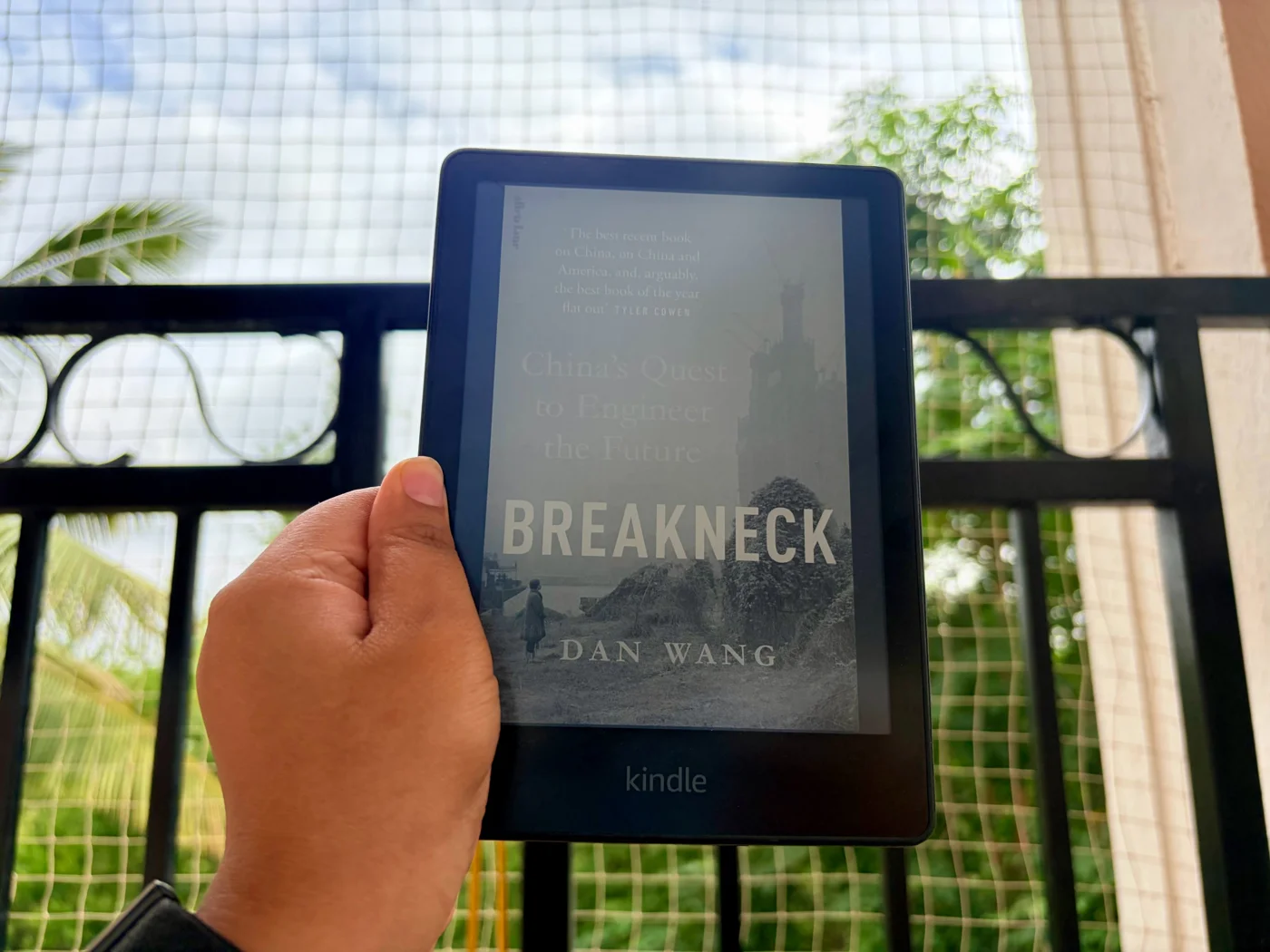 Sneha holding a Kindle displaying Breakneck by Dan Wang.